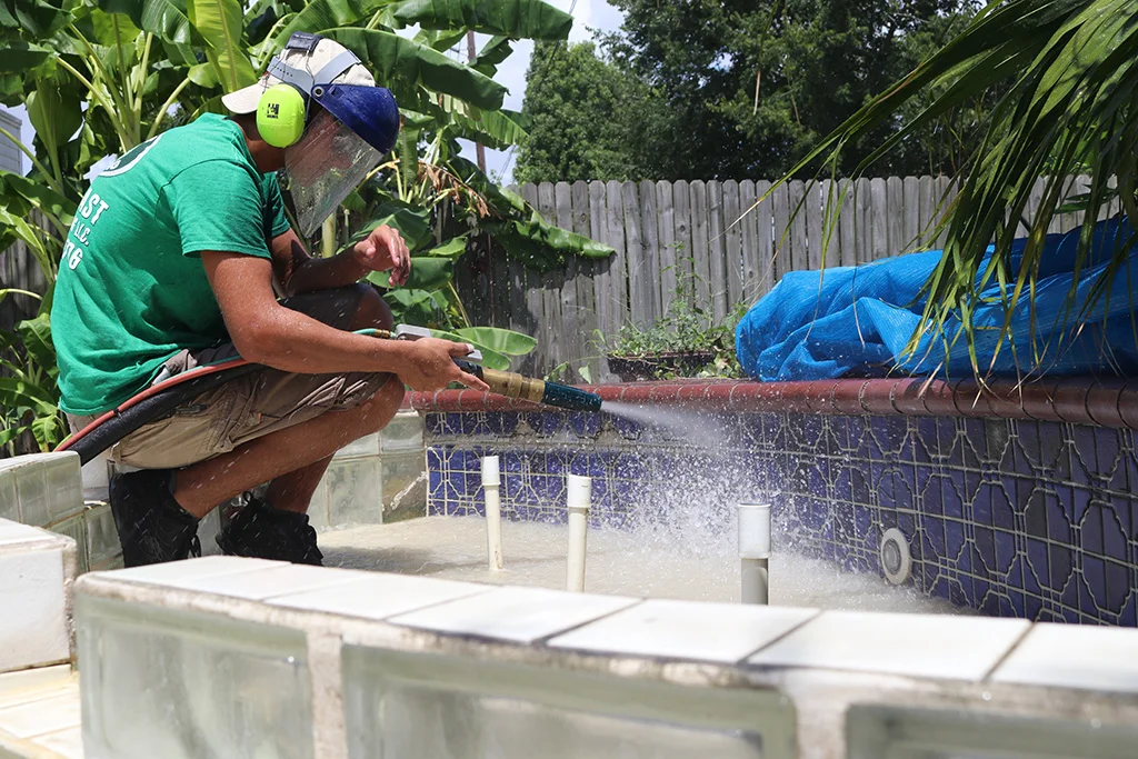 Man using a power tool to cut concrete near a pool.