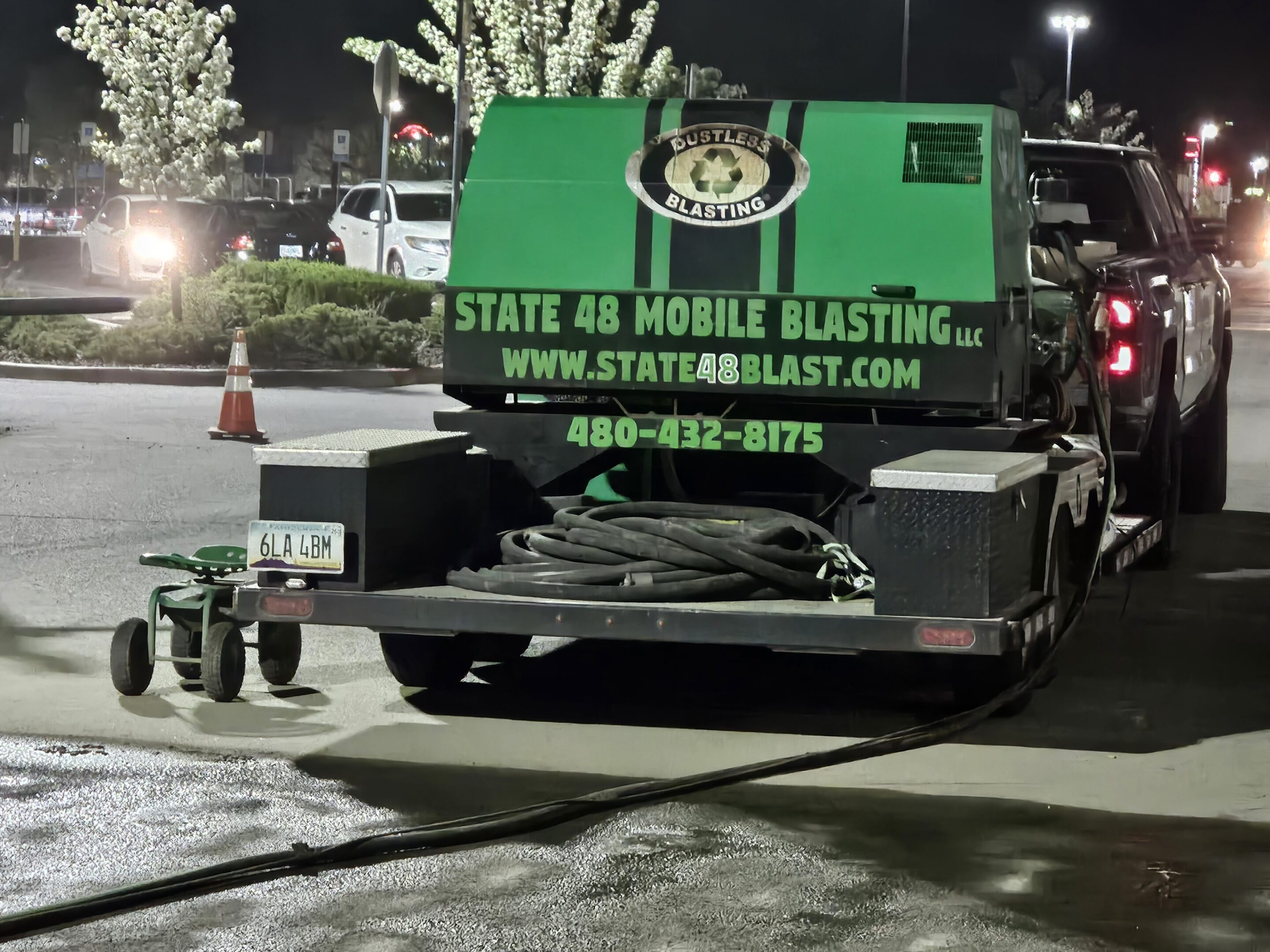 A truck with a green sign advertising mobile blasting services at night.