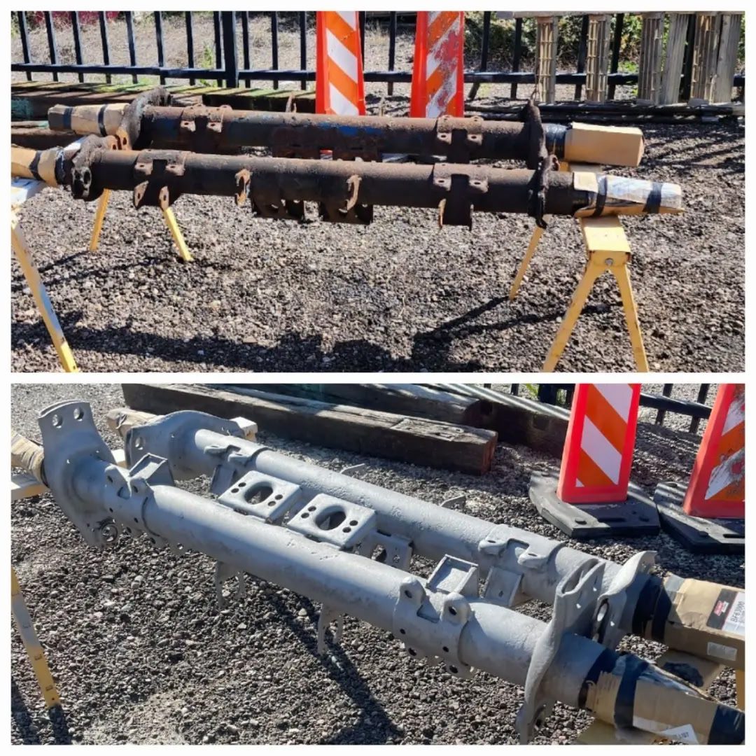 Comparison of two mechanical shafts, one new and one old, on a worksite.